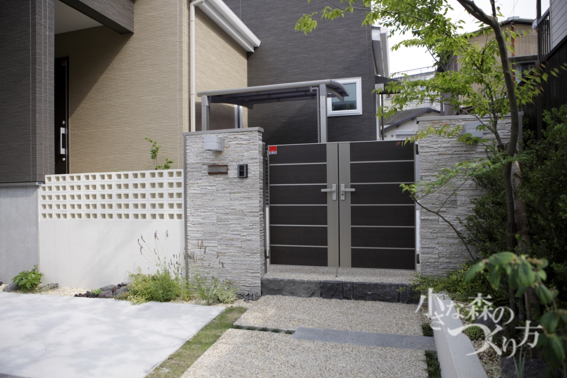 <p>外観はモダン。だけどどことなく和の趣漂う素敵なお家です。</p>
<p>複数の素材をバランスよく配したシャープなラインの外構。自然樹形の植栽で和風な柔らかさをだしています。</p>
<p>ボーダー石貼りの門柱。アルミの門扉にはダークブラウン(柿渋)カラーを選び落ち着きある門構えに。</p>
<p>ハードな素材(コンクリートや塗り壁など)がぶつかり合うような場所には、間に芝生や下草(タマリュウ)砂利などを少し入れてあげることで息苦しくなるのを和らげる効果があります。</p>